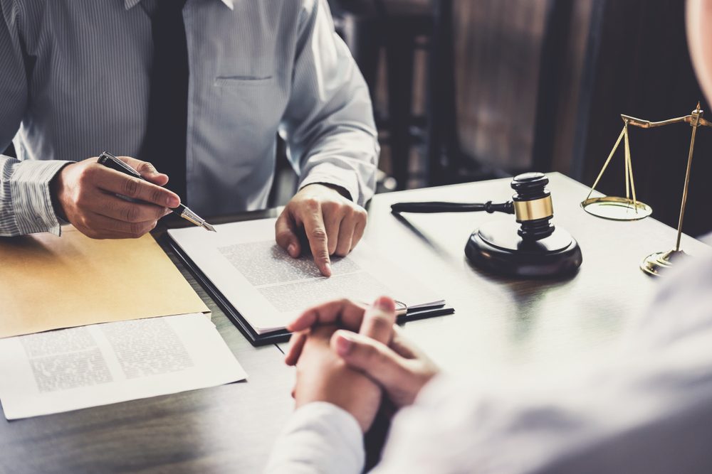 Lawyer sits at desk with client and explains how to file a workers’ comp claim in Georgia.