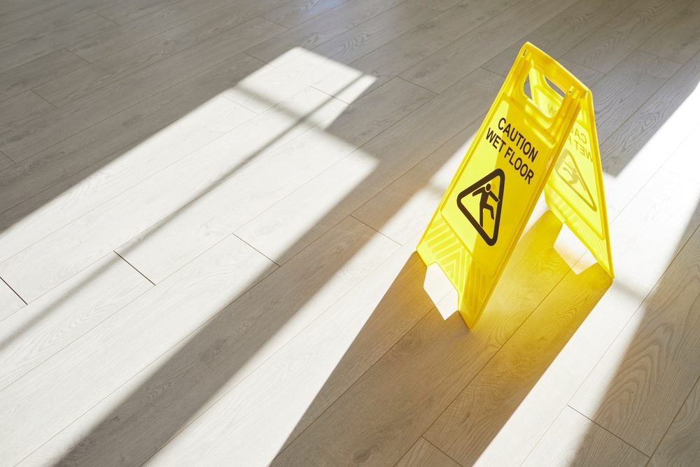 A yellow caution sign warns visitors about a wet floor. What is the average settlement for a slip and fall accident?