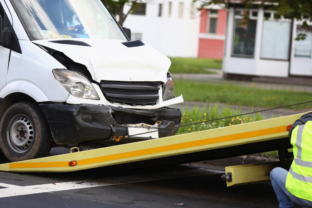 A driver loads a wrecked mail truck onto a tow truck after a crash, leaving them to wonder what happens if you get in an accident with a mail truck.