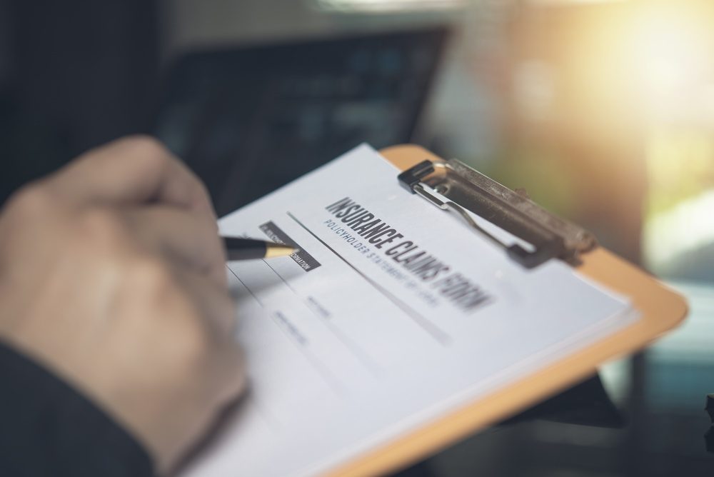 A person with GEICO insurance reviews an insurance claim form after a car accident.