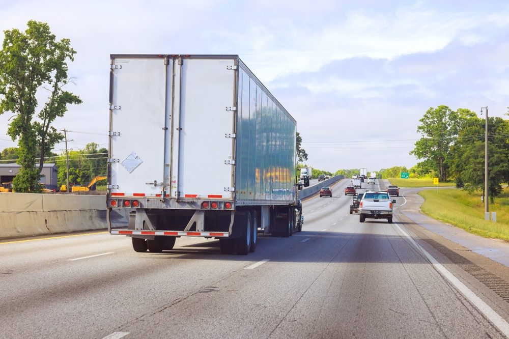 A commercial truck travels down a highway as nearby motorists wonder what a Jake brake is.