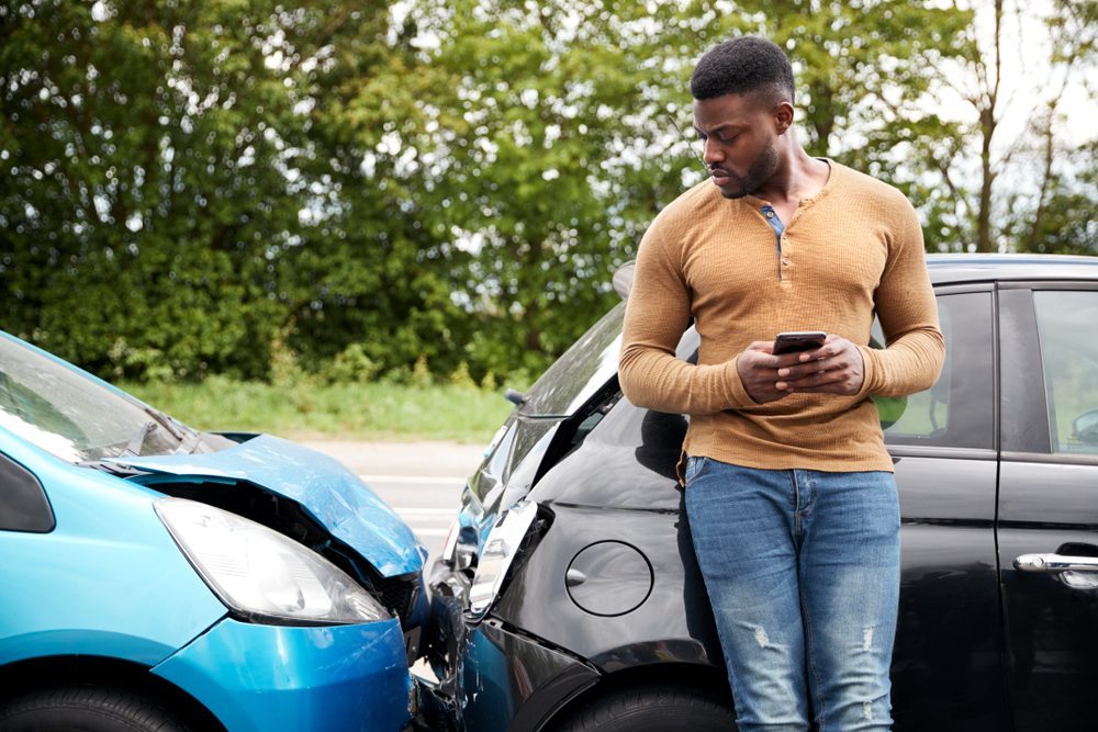A driver stands beside two cars after a front-end crash. Learn about the common types of auto accidents in Georgia.