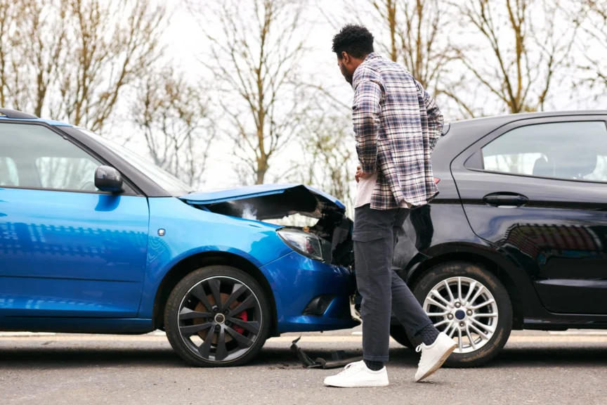 A man inspects his damaged car after a crash and wonders what to do if you get hit from behind.